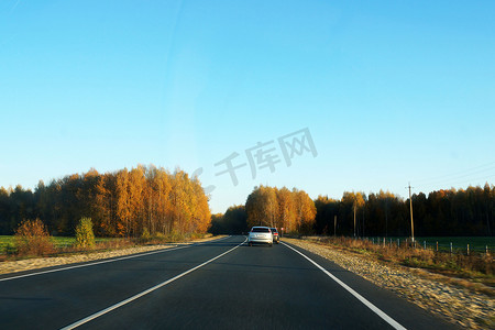 机动车路摄影照片_阳光明媚的秋日，森林背景的机动车路