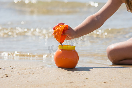 孩子在沙滩海边的锅里撒上模具里的湿沙