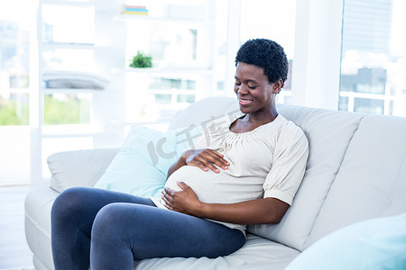摸着肚子摄影照片_孕妇坐在家里摸着肚子