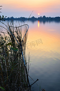 夕阳下的鱼竿和鱼缸在湖上钓鱼