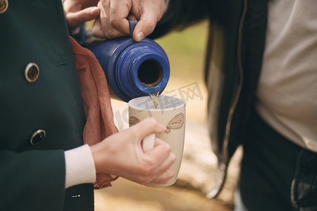 夫妻俩把热水瓶里的茶倒进杯子里，在 s 上热身