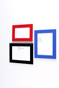 白色墙壁背景上的三个木制相框，红色、蓝色、黑色。