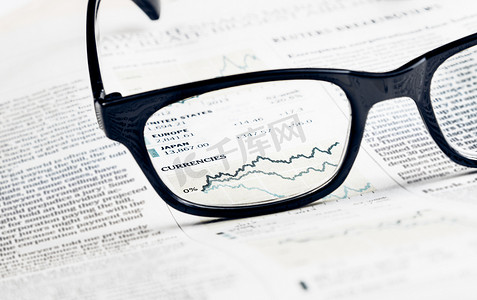 金融图表和图表货币透过金融报纸上的眼镜镜片