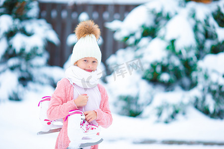 可爱的小女孩在冬天的雪天去溜冰场滑冰