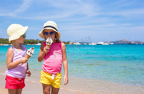 在热带海滩上吃冰淇淋的快乐小女孩