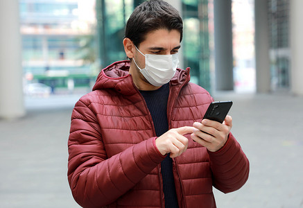 现代城市戴外科口罩的男子使用智能手机应用程序