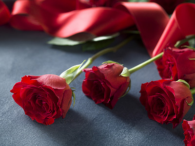 婚礼概念新鲜的红玫瑰和灰色蓝色纸上的红丝带
