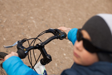 骑自行的男孩摄影照片_一个戴着墨镜的男孩坐在自行车上。