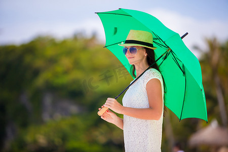 白色沙滩上带绿伞的年轻女孩