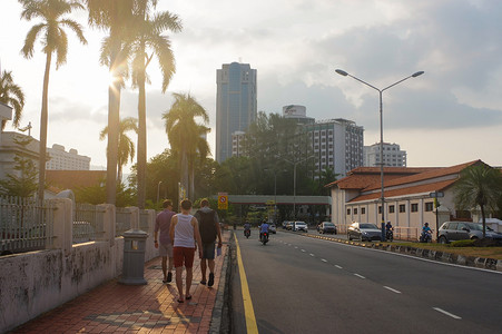 马来西亚槟城乔治城 — 2016 年 4 月 18 日：游客在乔治城的一条城市街道上，黄昏时分，有灯光小径和交通标志，乔治城。