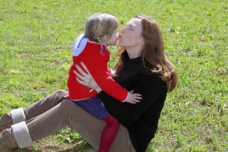 母亲和女儿在草地上亲吻嘴唇