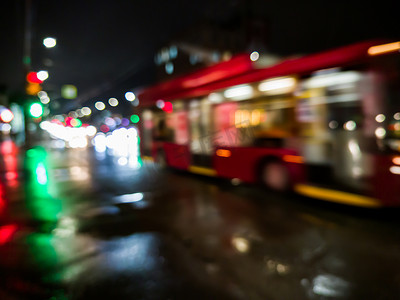 散焦的夜雨城市街景与红色巴士过马路