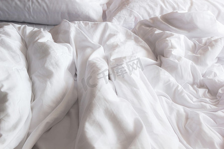 床上白色枕头的顶视图和皱纹凌乱的毯子我