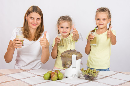 母亲和两个女儿竖起大拇指新鲜准备的果汁