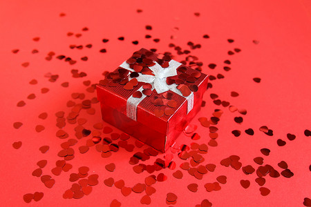 在明亮的背景的小红色礼物盒与装饰性小心脏金属丝。