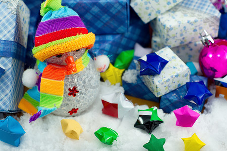 装饰小星星摄影照片_雪人和礼品盒与小星星纸在雪地上。
