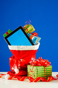 平板电脑与一堆礼物在红色袋子对蓝色酒泉