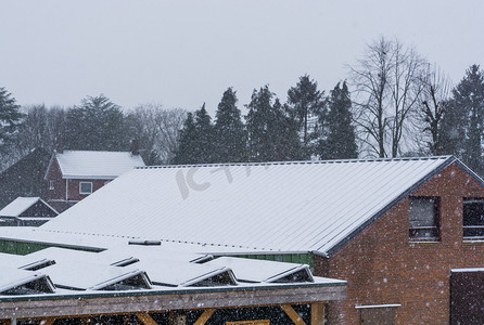 雪屋顶摄影照片_下雪天被雪覆盖的太阳能电池板，冬季的荷兰屋顶