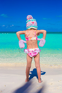 沙滩上戴着温暖针织帽和手套的可爱小女孩