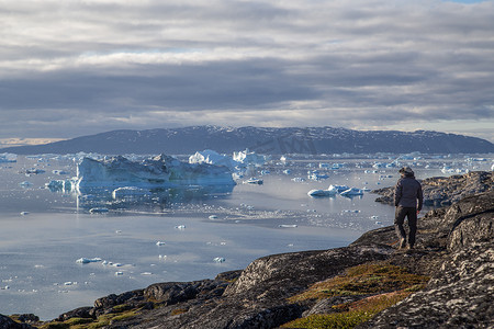 冰山摄影照片_男子在格陵兰罗德贝看冰山