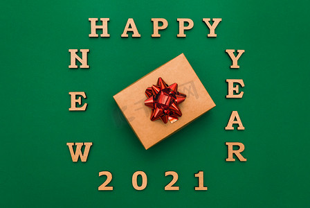 2021 年新年快乐贺卡。圣诞边框与工艺礼品盒和绿色背景的红色蝴蝶结。