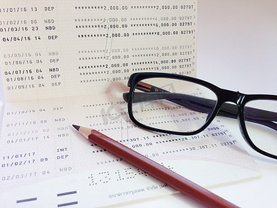 白色背景中的铅笔、眼镜和储蓄账户存折或财务报表