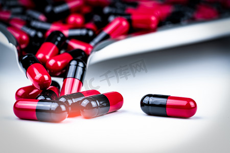 红色和黑色胶囊药丸在不锈钢药盘上的选择性聚焦。