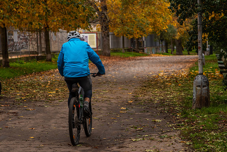 秋季保健摄影照片_2020 年秋季，捷克共和国冬季开始时，由于 COVID-19 的爆发，一名男子正在布拉格 6 号的 Stromovka 公园骑自行车