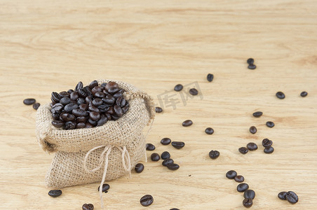 咖啡咖啡豆面包摄影照片_袋装咖啡豆，咖啡豆铺在木头上