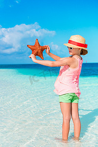 白色空荡荡的海滩上有海星的可爱小女孩