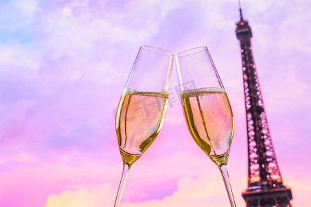 模糊的埃菲尔铁塔背景上一对带有金色气泡的香槟长笛