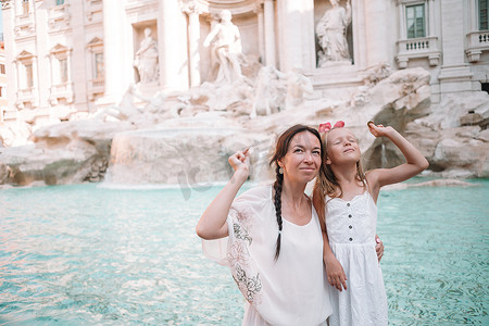 古代钱币摄影照片_年轻漂亮的女人和小女孩靠近喷泉 Fontana di Trevi