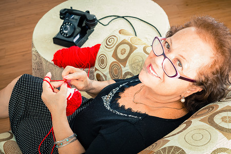 扶老人摄影照片_年长的祖母坐着享受她的编织