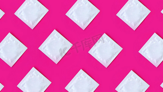预防艾滋病病毒摄影照片_粉红色背景中排成一排的许多避孕套