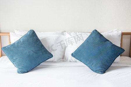 床上有白色枕头和蓝色枕头，卧室里有毯子