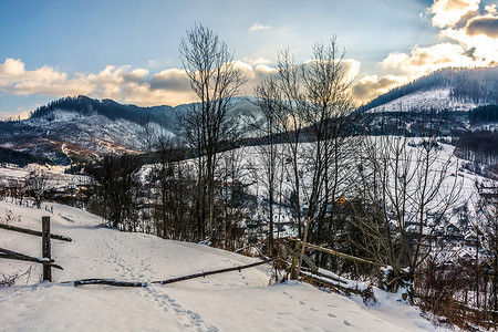 冬天在山区附近白雪皑皑的乡村田野上围栏