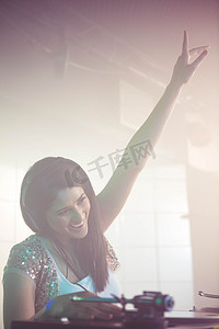 dj酒吧摄影照片_漂亮的女 DJ 在播放音乐时挥舞着她的手