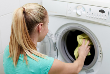 快乐的女人在家里把要洗的衣服放进洗衣机
