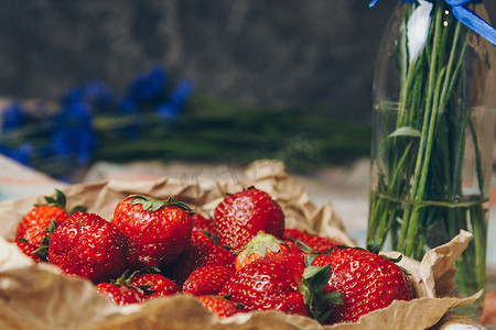 纸上花摄影照片_餐巾纸上的时令夏花蓝色矢车菊和水果草莓特写概念背景