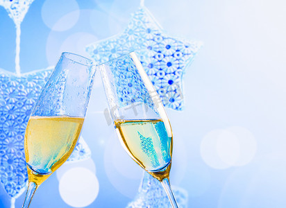 蓝色圣诞灯装饰背景上带金色气泡的香槟长笛