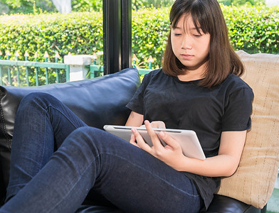 s型摄影照片_在客厅用数字平板电脑在线学习的年轻女孩