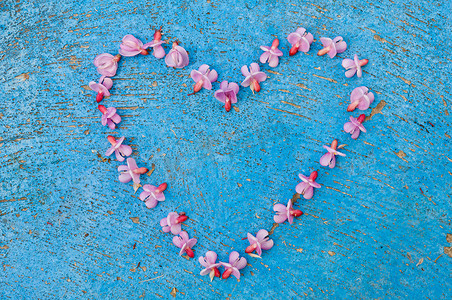 由粉红色花朵在旧质地浅蓝色上形成的心形
