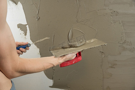 抹墙施工摄影照片_一名工人用抹刀抹墙，并涂上水泥 m
