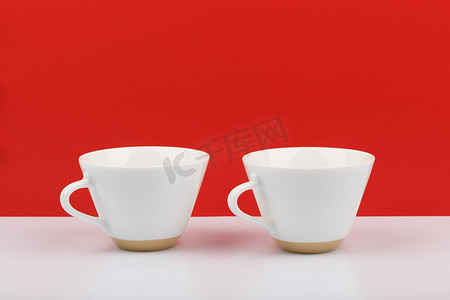 红色背景下白桌上的两个白色陶瓷咖啡杯，有文字空间
