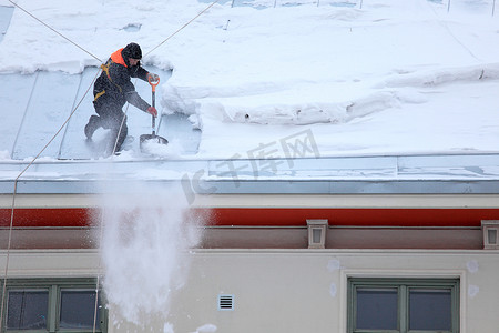男人正在给多雪的屋顶除冰