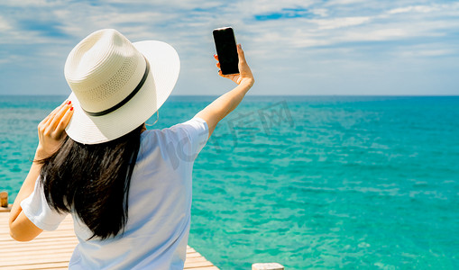 年轻的亚洲女性戴着休闲风格的草帽使用智能手机