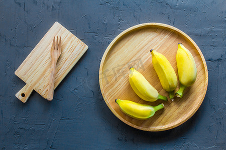 成熟的香蕉在黑墙背景上的木板。