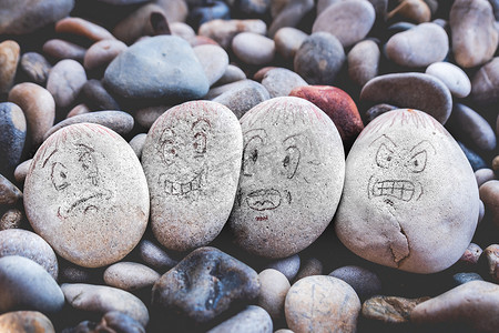 豆豆表情包摄影照片_管理石头上的情绪表情符号面孔-悲伤、快乐、惊讶、担心和愤怒的画