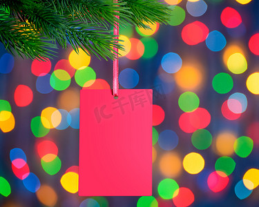 节日灯光背景下冷杉枝上的圣诞贺卡