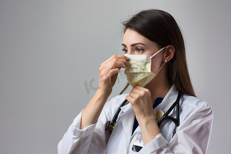女性医疗保健专业人员展示正确戴上口罩以防止冠状病毒感染。